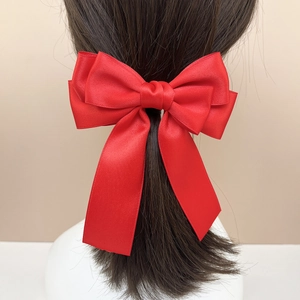 Close-up of red multi-layer satin ribbon bow hair clip on long dark brown hair