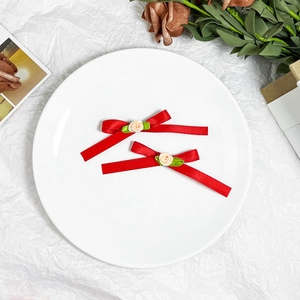 Detail of red satin bow hair clips with pink fabric roses on a white ceramic plate