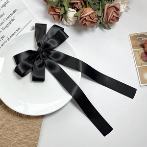 Détail d'un nœud papillon en satin noir avec de longs rubans sur une assiette
