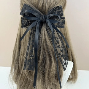 Detailed view of elegant black lace and satin ribbon bow hair clip on a model
