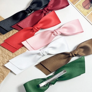 Elegantes Set aus bunten Satin-Haarschleifen mit Metall-Krokodilklemmen auf weißem Grund