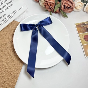 Detailopname van donkerblauwe satijnen haarstrik met lange linten op vintage achtergrond