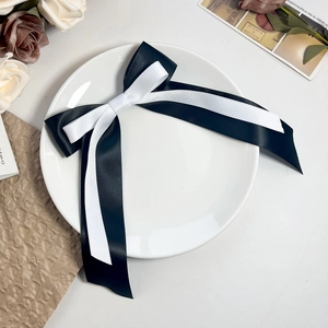 Détail de la pince à cheveux double nœud en soie avec longs rubans sur une assiette blanche