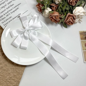 Détail d'un nœud en satin blanc avec rubans élégants sur un fond décoratif chic