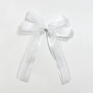 Detailed view of white mesh bow hair clip with elegant long streamers and sheer fabric