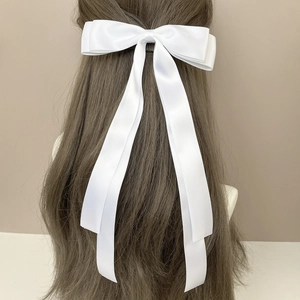 Detail showing elegant white satin bow hair clip with long streamers on long hair