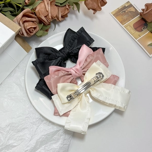 Trois barrettes nœuds en satin noir, rose et beige avec volants et clips métalliques