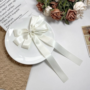 Détail d'un nœud à cheveux en satin crème avec de longs rubans sur fond floral vintage