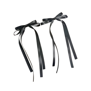 Pair of elegant black satin bow hair clips with long streaming ribbons on white background