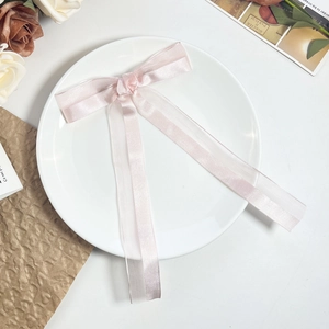 Detailed view of pink mesh bow hairpin with satin and organza on a white plate