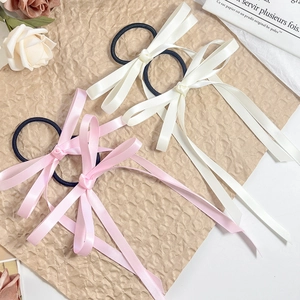 Pink and beige long satin ribbon bow hair ties on textured paper with roses