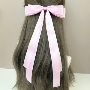 Elegant long pink satin bow hair clip with streamers shown on brown hair model