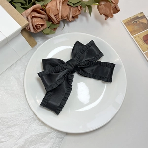 Détail d'un nœud papillon en satin noir avec bords volantés sur porcelaine blanche