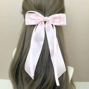 Pince à cheveux noeud en soie rose avec perle et long ruban sur un mannequin