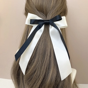 Détail d'une barrette à cheveux en satin noir et blanc à double couche sur cheveux longs