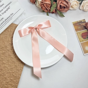 Detailopname van een roze satijnen harikstrik met lange linten op een wit keramisch bord