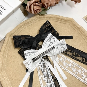 Elegant lace bow hair clips with long ribbons in black and white styles on a tray