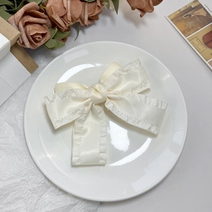 Détail d'un nœud papillon en satin crème avec bords à volants sur une assiette blanche