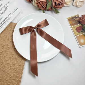 Detailopname van een donkerbruine satijnen strik haarclip op een vintage decoratief bord
