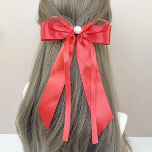Détail du nœud papillon en satin rouge avec longs rubans et perle blanche élégante