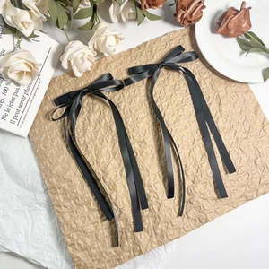 Close-up of elegant black satin ribbon bow hair clips on aesthetic vintage paper
