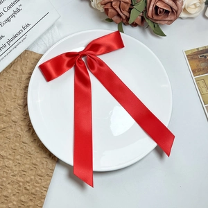 Detailopname van een grote rode satijnen haarstrik op een wit decoratief bord