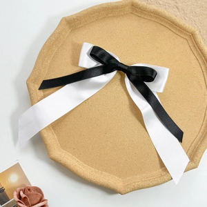 Détail du nœud papillon en satin noir et blanc double couche sur un plateau en liège