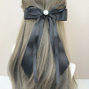 Barrette à nœud en satin noir élégante avec perle sur mannequin de cheveux doux