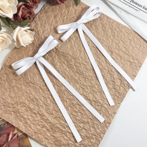 Detail of white ribbon bow hair clips with long streamers on a vintage background