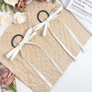 Elegant set of two cream ribbon bow hair ties with long satin streamers on a vintage background