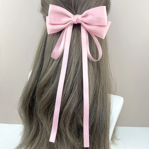 Barrette élégante en satin rose avec long ruban sur une chevelure ondulée