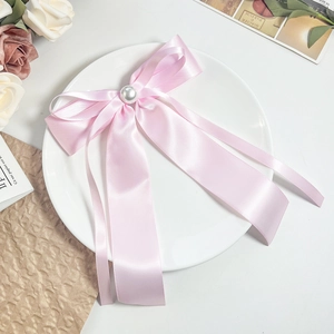 Détail du nœud papillon en satin rose avec perle sur un présentoir décoratif vintage
