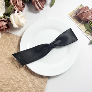 Nahaufnahme der schwarzen Satin-Schleife Haarspange auf einem eleganten weißen Teller