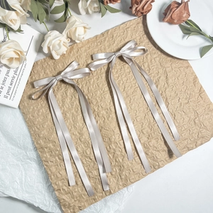 Detail of long silver satin bow hair clips with silk texture on vintage paper