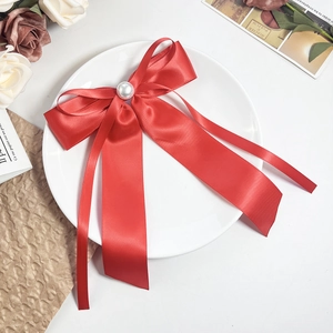 Détail d'une barrette à cheveux nœud en satin rouge avec perle sur fond vintage élégant