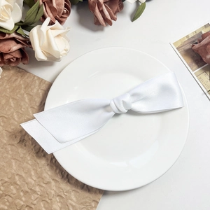 Detail einer eleganten weißen Schleifen-Haarspange auf Dekoteller mit Rosen