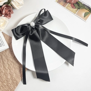 Vue détaillée d'un nœud en satin noir avec perle sur une assiette en porcelaine blanche
