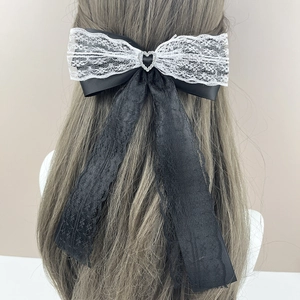 Close-up of black lace bow hair clip with heart rhinestone and long silk ribbons