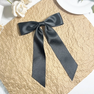 Detailed view of elegant black satin ribbon bow hair clip on rustic paper background