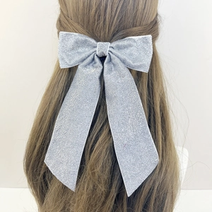 Élégante grande barrette à nœud argenté scintillant sur de longs cheveux bouclés, style français