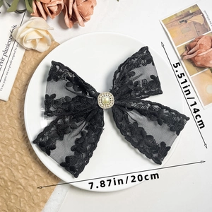 Detailed shot of black lace bow hair clip with square green gemstone and micro pearls