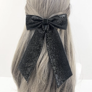 Barrette nœud papillon noir scintillant avec longs rubans sur cheveux blonds bouclés