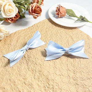 Dettaglio di fermagli per capelli in raso azzurro con texture in seta e design a fiocco a strati