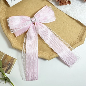 Close-up of pink silk bow hairclip with white lace and heart rhinestone in a tray