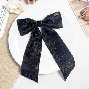 Gros plan d'une pince à cheveux nœud noir scintillant sur une assiette blanche élégante