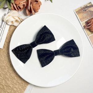 Sparkling black bow hair clips set of two with sequins on elegant white ceramic plate