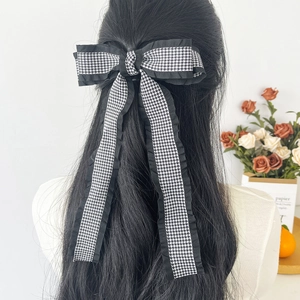 Elegant houndstooth bow hair clip with long ribbons and black ruffled edges on long hair