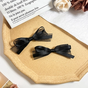 Lot de deux barrettes à nœuds en satin et résille noirs sur plateau décoratif