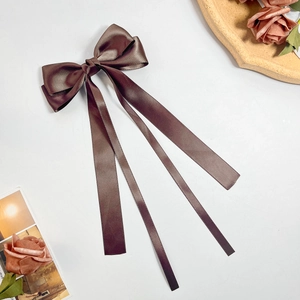 Detailed view of dark brown satin ribbon bow hair clip with elegant long streamers
