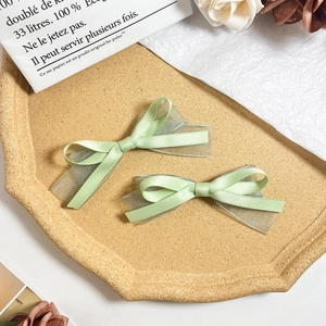 Détail des barrettes à cheveux à double nœud vert clair en satin et texture organza
